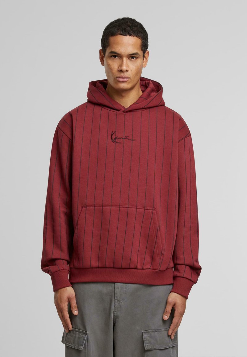 Hoodie bordeaux avec des rayures verticales bleu marine, capuche avec cordon de serrage, poche ventrale et logo brodé sur la poitrine. Matériau en mélange de coton.