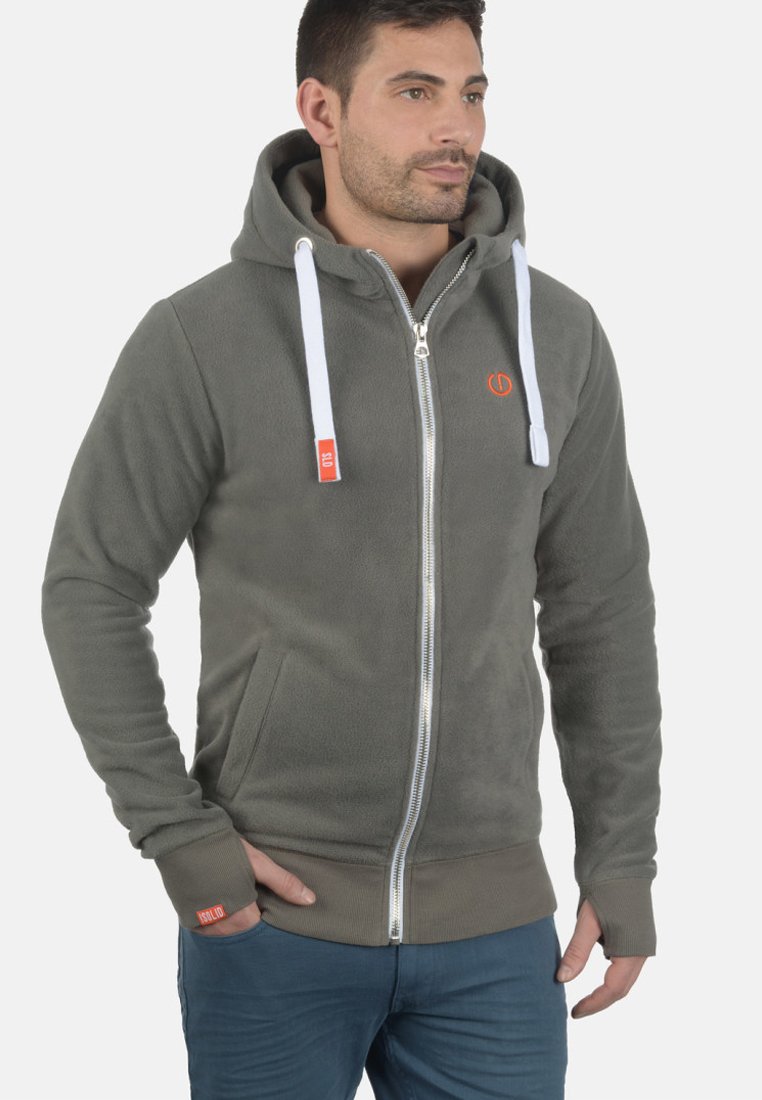 Gray fleece zip-up hoodie with white drawstrings, side pockets, and red brand logo. Soft texture and fitted design.