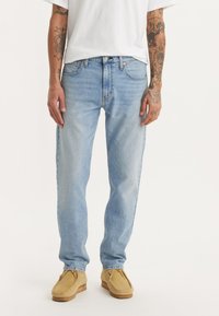 Lichtblauwe spijkerbroek van denim, met een rechte snit en vijf-pocket ontwerp. Gecombineerd met beige mocassinschoenen.
