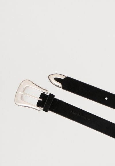 Μαύρη δερμάτινη ζώνη με ασημένιο μεταλλικό πόρπη σε μοναδικό σχήμα και υφή. Ο ιμάντας έχει λεία επιφάνεια και ταυτοποιημένο λογότυπο.