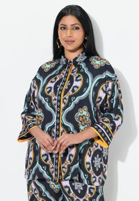 Schwarze und mehrfarbige gemusterte Bluse mit Kragen, langen Ärmeln und orangefarbenen Akzenten. Verfügt über aufwendige florale und wellenförmige Muster.