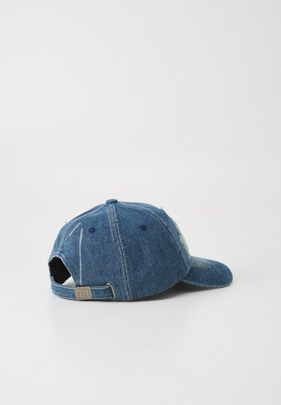 Boné de basebol em denim azul com aba curva, fita ajustável e detalhe de logo bordado na lateral. A superfície tem um acabamento texturizado.