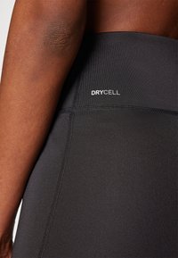 Sorte trænings leggings med et glat, strækbart stof, en tekstureret talje, et "DRYCELL" logo og flade sømme for komfort.