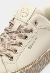 Μπεζ αθλητικά παπούτσια με κα patterned σατέν κορδόνια, χρυσά μάτια, μεταλλικό λογότυπο της μάρκας και χοντρή σόλα με animal print και χρυσή διακόσμηση.