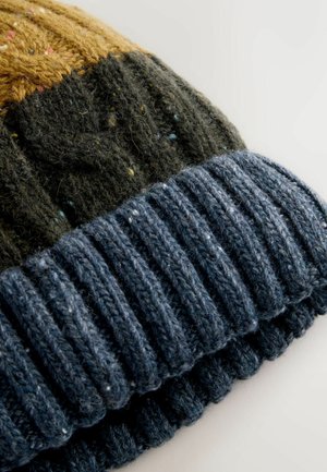 Gebreide beanie met een patroon van donkere groene, gele en marineblauwe secties; rib gebreide marineblauwe omslag; zachte textuur met veelkleurige spikkels.