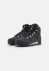 Botas de senderismo negras con parte superior de ante y nylon, que presentan ganchos de metal para los cordones, una suela resistente y acentos texturizados para mayor agarre y soporte.
