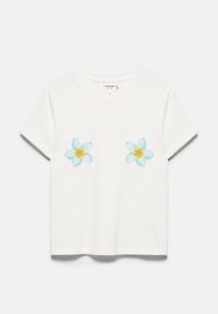 T-shirt blanc à manches courtes avec deux motifs de fleurs tropicales bleues et jaunes sur la poitrine, col rond et fond uni.