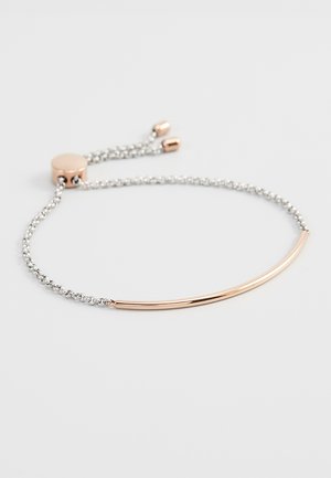 Bracelet chaîne en argent avec une barre incurvée en or rose et un fermoir coulissant réglable en or rose sur fond blanc.