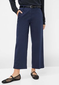 Marineblauwe wijde broek gemaakt van lichtgewicht stof, met een rechte snit en zijzakken, gecombineerd met zwarte mesh ballerina's.