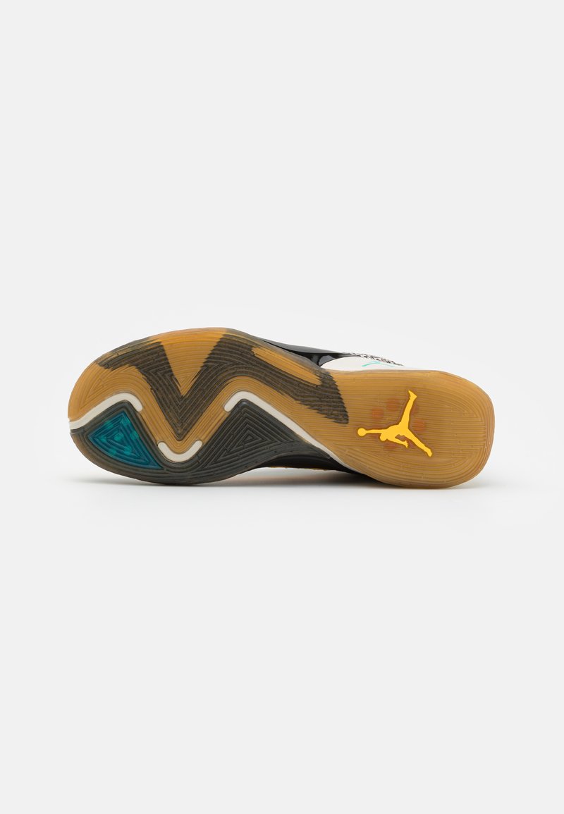 Semelle de chaussure Air Jordan avec un design en caoutchouc noir et gomme. Présente un motif en zigzag, des accents bleus translucides et un logo jaune.