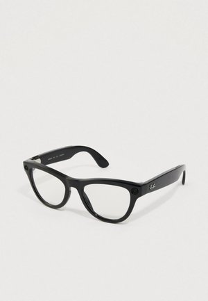 Gafas Ray-Ban negras rectangulares con lentes transparentes descansando sobre una superficie clara, mostrando el logotipo plateado en la patilla.