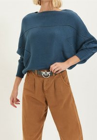 Blauwe gebreide trui met een losse pasvorm en een gestructureerd patroon. Gecombineerd met hoge bruine corduroybroeken en een riem met zilveren details.