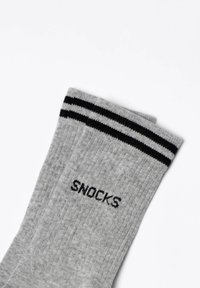 Graue gestrickte Socken mit schwarzen Streifen oben und "SNOCKS" in Schwarz bedruckt. Baumwollmischung, weiche Textur, Design in Knöchellänge.
