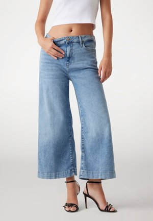 Jeans in denim di un blu chiaro a gamba larga, con vita alta, tasche frontali e una finitura denim sbiadita con orlo grezzo.