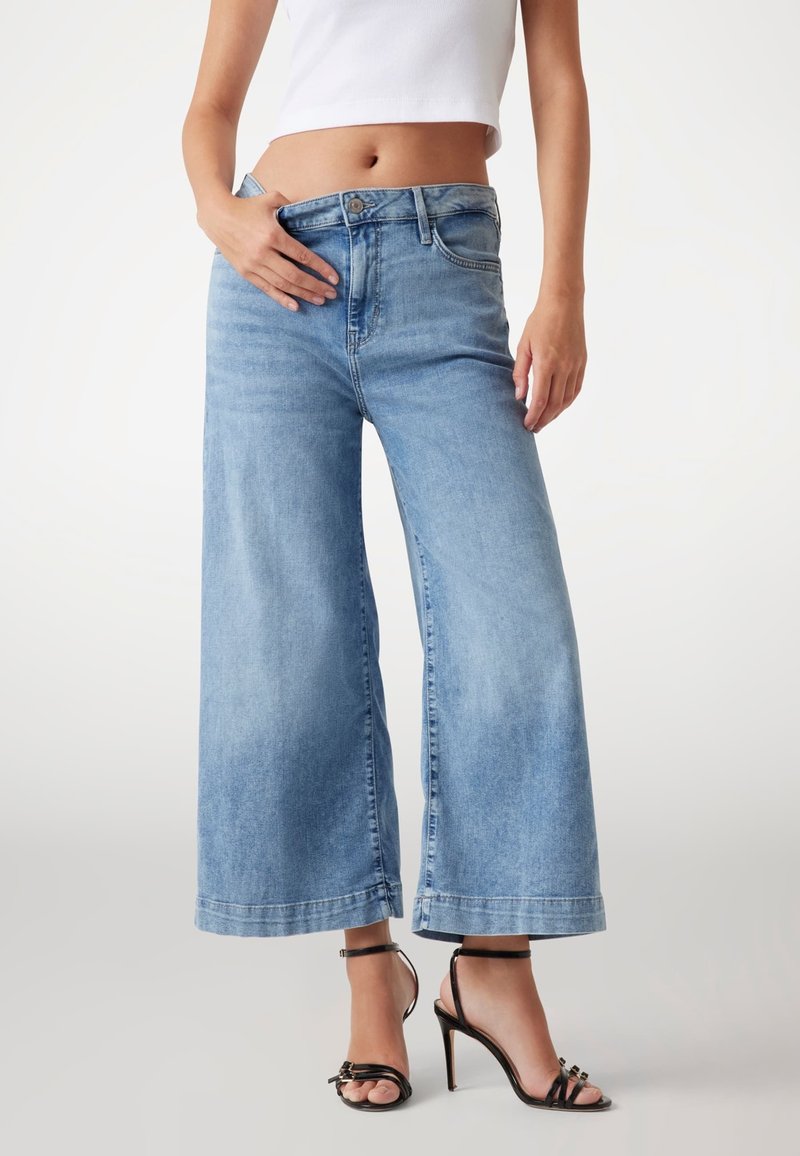 Jeans in denim di un blu chiaro a gamba larga, con vita alta, tasche frontali e una finitura denim sbiadita con orlo grezzo.