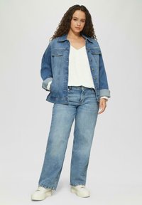 Lichtblauwe denimjack en jeans set, met een ontspannen pasvorm, knopenlijst en omgeslagen mouwen. Een wit topje eronder maakt de outfit compleet.