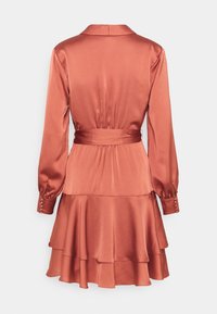 Abito in satin color ruggine con collo a camicia, maniche lunghe e orlo a volant a strati. Presenta una cintura con lacci e dettagli a bottoni sulle maniche.
