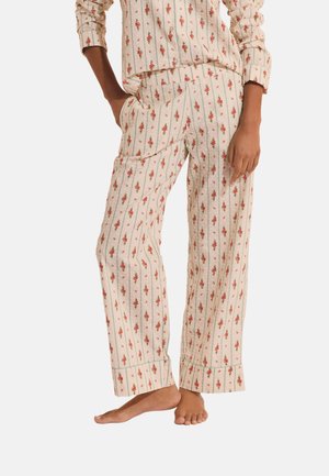 Ensemble de pyjama couleur crème avec un petit motif floral rouge et rayures verticales, pantalon ample et haut à manches longues, personne pieds nus debout.