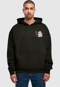 Schwarze Kapuzenjacke mit einer Fronttasche und einem Gespenst-Grafikdesign mit dem Text "Boo to You" im linken Brustbereich. Weicher Stoff und lässige Passform.