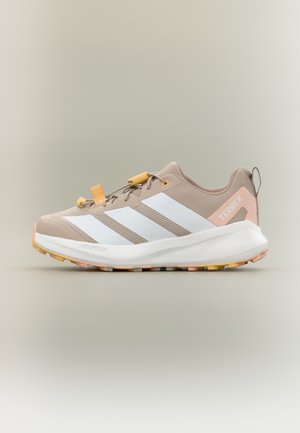 Αθλητικό παπούτσι σε ανοιχτό μπεζ χρώμα με λευκές ρίγες, διαθέτει υφασμένο πάνω μέρος, κίτρινο σύστημα κορδονιών και πολύχρωμη εξωτερική σόλα για πρόσφυση.