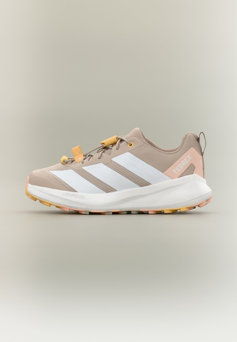 Αθλητικό παπούτσι σε ανοιχτό μπεζ χρώμα με λευκές ρίγες, διαθέτει υφασμένο πάνω μέρος, κίτρινο σύστημα κορδονιών και πολύχρωμη εξωτερική σόλα για πρόσφυση.