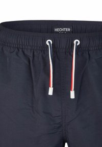 Marine zwembroek met elastische tailleband en trekkoord. Kenmerkt zich door rode, witte en blauwe accenten op het trekkoord. Label leest "HECHTER PARIS."