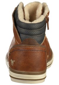Bottine en cuir marron avec un panneau texturé bleu marine, doublure en fourrure crème et semelle en caoutchouc beige clair. Présente des coutures décoratives.