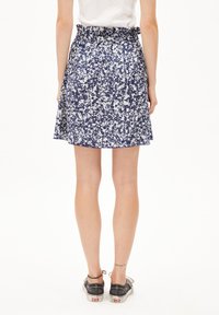 Floral-patterned skirt in navy and white, featuring a ruffled waistband, a flared silhouette, and a lightweight fabric. Casual design pairs with sneakers.