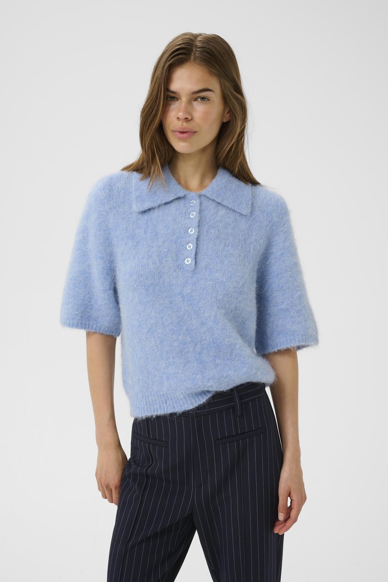 Light blue wool-blend sweater with short sleeves, large collar, and button placket. Paired with navy pinstriped trousers. Soft texture.