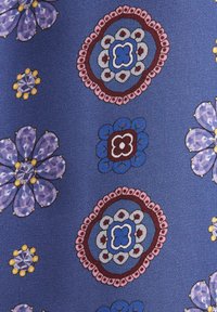 Tissu bleu avec motifs floraux répétitifs en violet, rose, blanc, jaune et rouge, présentant des formes circulaires et en pétales sur une surface texturée.