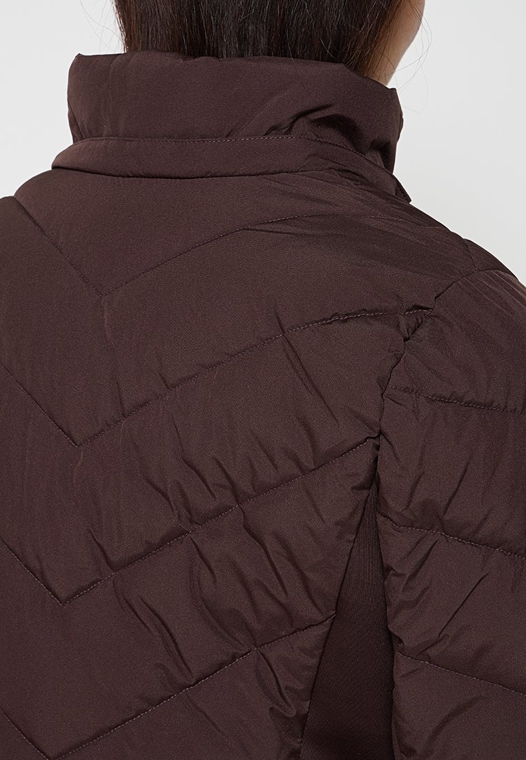 Persoon in een donkerbruin gewatteerd jack gezien vanaf de achterkant, met de nadruk op de kraag en stikdetails.