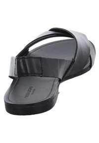 Musta avonainen sandaali, jossa on kaksi leveää nahkaremmiä, jotka risteävät jalkaterän päällä, ja pehmeä pohja.