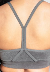Sujeción deportiva gris con una textura suave, tirantes finos ajustables y un diseño de espalda en forma de Y. Tela elástica con una banda ceñida.