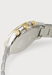 Silver and gold-tone wristwatch featuring a stainless steel band, prominent round case with three pushers, and a smooth, shiny finish.