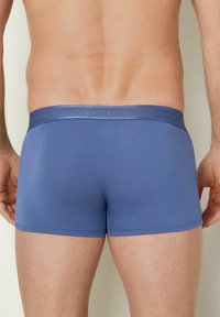 Blå boxerkalsonger i en smidig tyg, med en smal midjeresår med präglad logotyp, och en figurnära design som följer kroppens konturer.