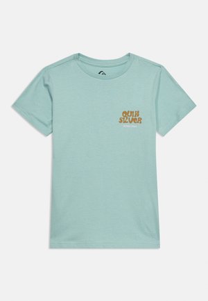 Ανοιχτό μπλε κοντομάνικη μπλούζα με στρογγυλή λαιμόκοψη και μικρό καφέ κείμενο "Quiksilver Since 1969" στο αριστερό στήθος.