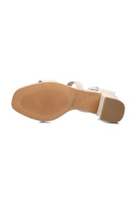 Witte sandalen met hakken, voorzien van een gladde leren bovenkant, een verstelbare enkelband en een gestructureerde rubberen zool met horizontale groeven voor grip.