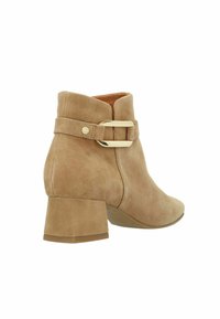 Tan suède enkellaars met een ronde neus, chunky hak en een verstelbare gesp aan de zijkant. Gladde textuur met minimale stiksels.