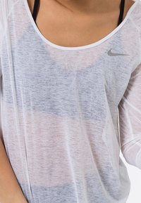 Lightweight, sheer white top with blue and gray horizontal stripes, featuring a scoop neckline and a small gray Nike logo on the chest.