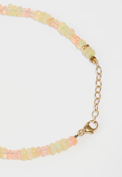 Collar de cuentas colorido con cuentas translúcidas amarillas y rosas, que cuenta con un cierre y conector de cadena en tono dorado. Formas suaves y redondeadas.