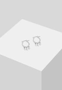 Silverfärgade hoopörhängen med hängande stjärnor och halvmånecharms, som har en polerad finish och cirkulär design.