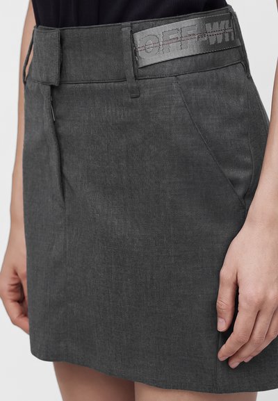Jupe gris foncé avec poches latérales et une large ceinture comportant une sangle intégrée avec le nom de la marque partiellement visible.