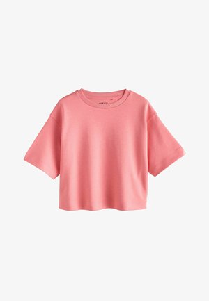 T-shirt crop à manches courtes en tissu rose pâle doux. Il présente un col rond et une coupe décontractée. Texture lisse avec des détails de couture subtils.