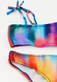 To-delt bikini sæt med et multifarvet gradientmønster, lavet af glat stof med kontrastsyninger og justerbare tie straps.