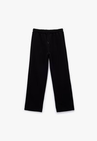 Svarta sweatpants i mjukt tyg, med dragsko i midjan, sidofickor och en lös passform. Inga mönster eller ytterligare detaljer.
