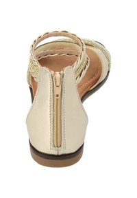 Heller beiger Sandale mit einer strukturierten Lederoberfläche, geflochtenen Riemen und einem Reißverschluss auf der Rückseite. Flache Sohle mit einer braunen Gummisohle.