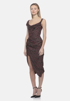 Donna in piedi che indossa un abito midi nero senza maniche con motivo astratto rosso, scollo a drappeggio, spacco laterale e tacchi neri con cinturino alla caviglia.