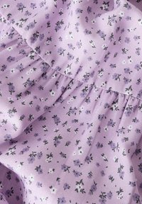 Tejido de lavanda con pequeños y delicados patrones florales en tonos de púrpura y blanco. Material suave y texturizado con detalles fruncidos.