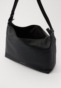 Black leather hobo bag with a textured surface, zipper closure, and adjustable fabric strap. Features a subtle logo on the front.