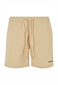 Bežové plavky vyrobené z ľahkého materiálu. Obsahujú elastický pás so šnúrkou a potlačeným logom v blízkosti lemu.